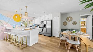A modern kitchen with white cabinetry, stainless steel appliances, and a central island with bar stools.
