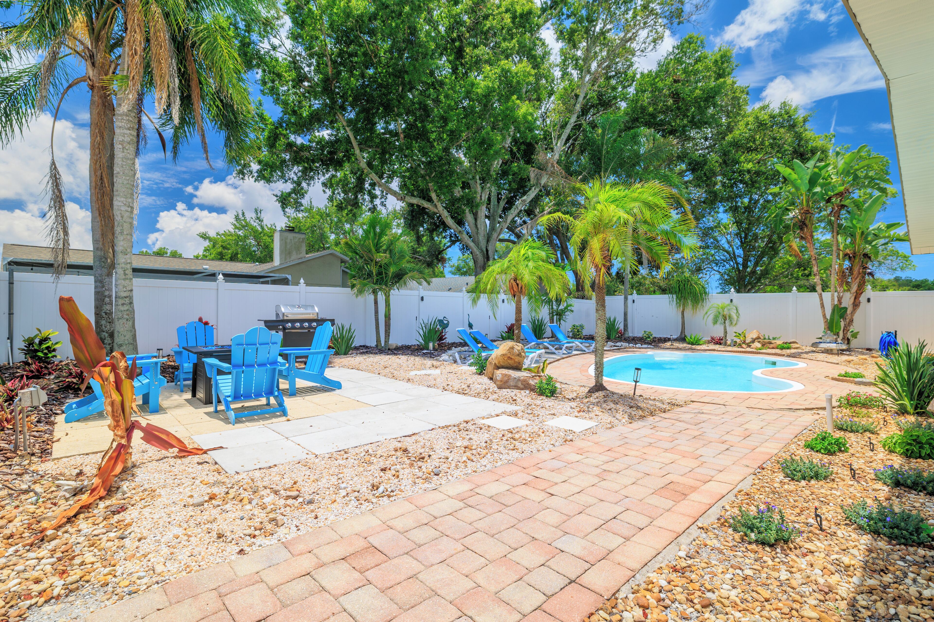 A backyard with a pool, patio furniture, and a barbecue area.