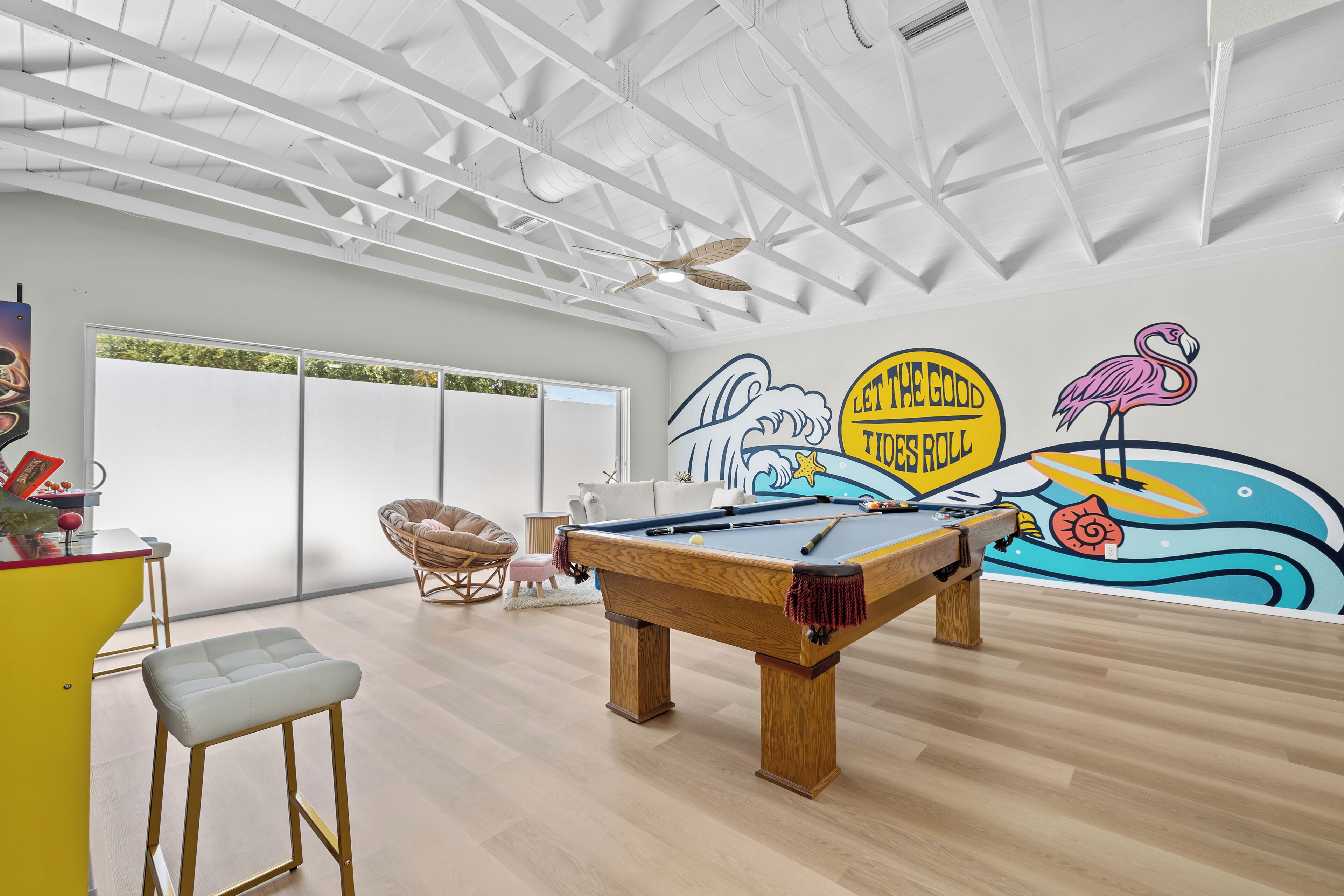 A pool table in a room with a high ceiling and a mural on the wall.