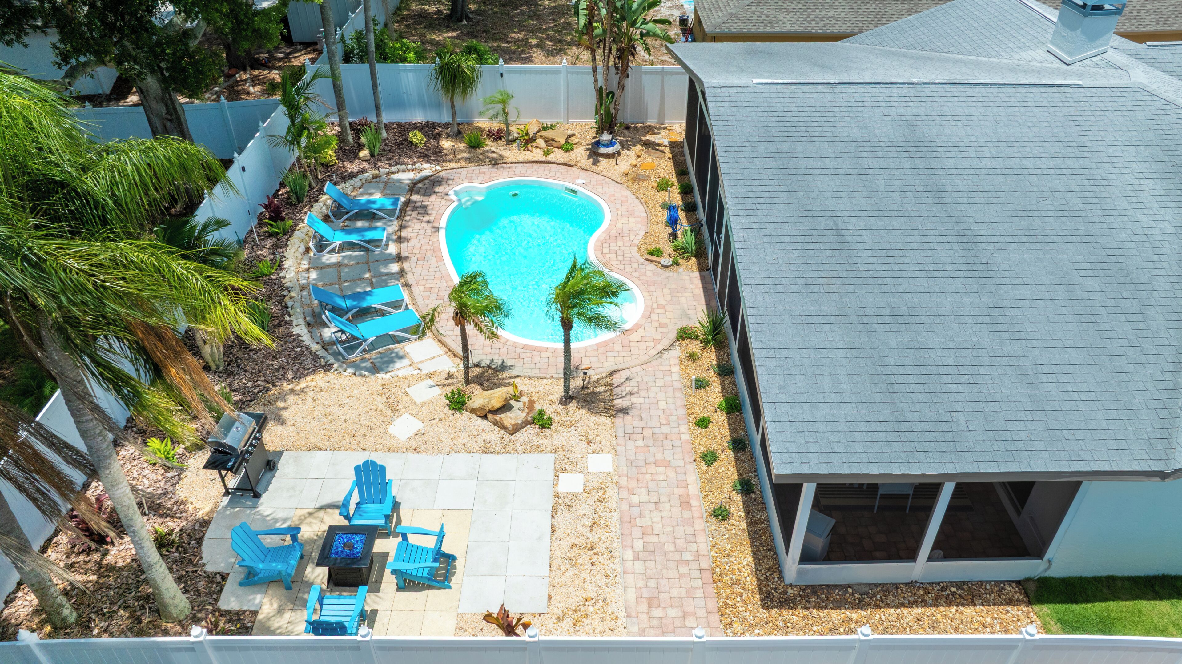 A residential backyard with a swimming pool, patio furniture, and a small deck.