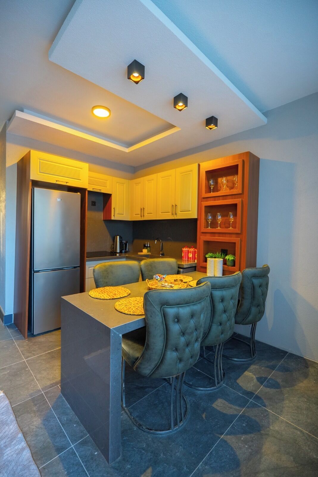 A modern kitchen with a central island, built-in cabinets, and a refrigerator.