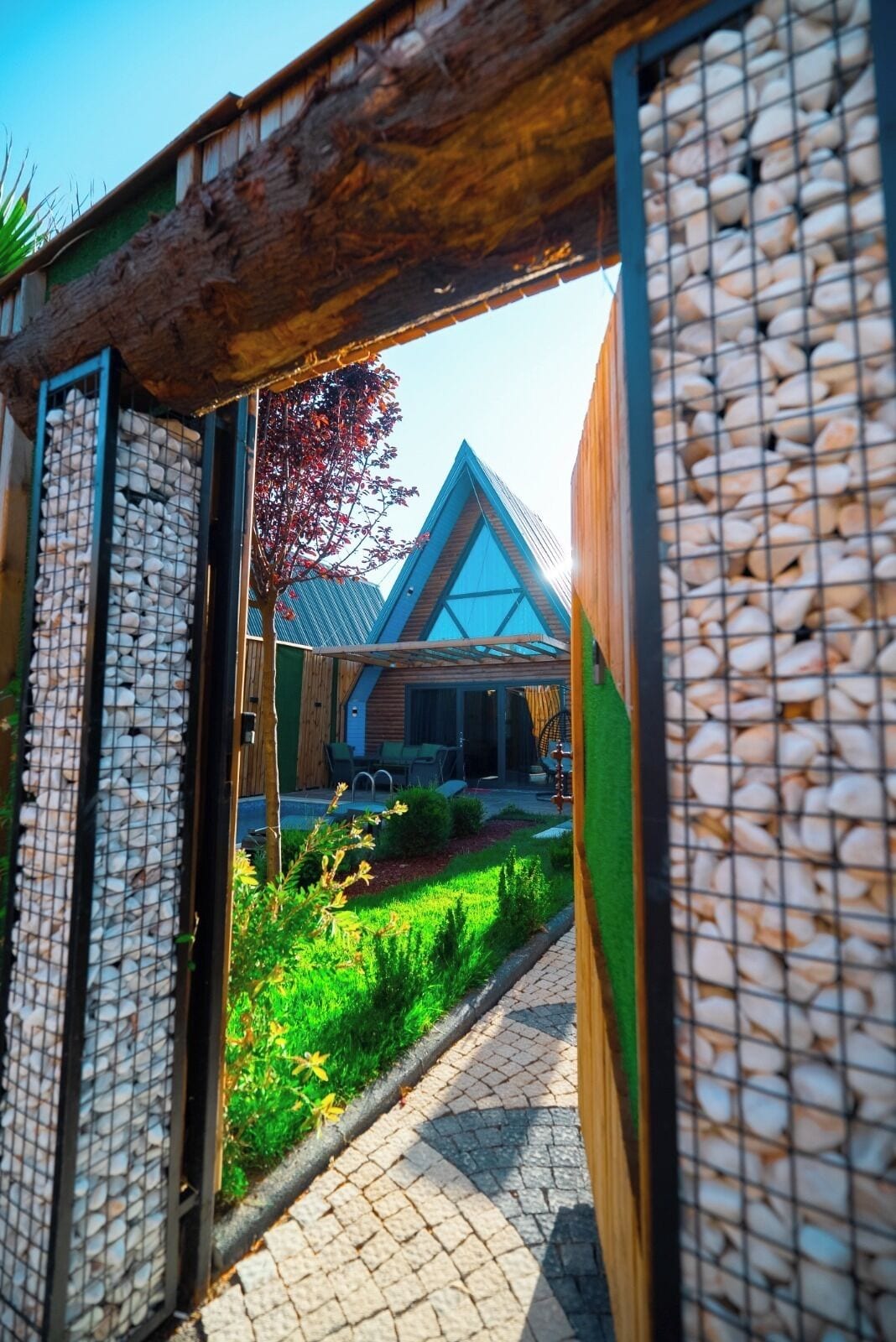 A modern building with a triangular roof and a garden in front.