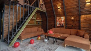 A loft-style room with a wooden ceiling, a staircase, a sofa, a table, and a painting. - Berra Resort (Sapanca)