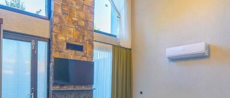 Una sala de estar moderna con chimenea de piedra, un sofá verde, una mesa de centro de madera y una lámpara de techo.
