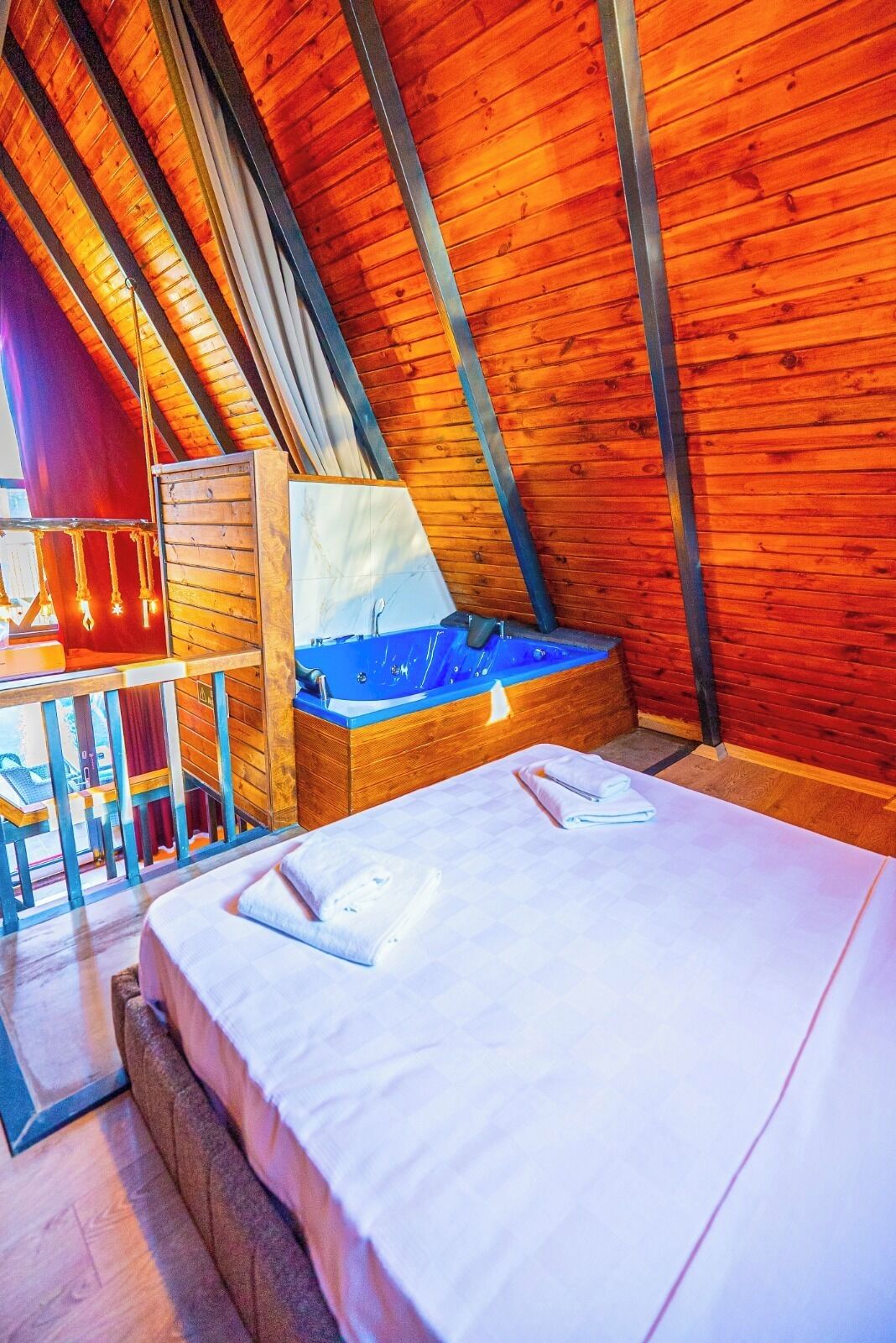 Une pièce avec un plafond en pente, un lit, un bureau en bois et une baignoire bleue.