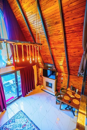A cozy interior with a wooden ceiling, a fireplace, a television, and a dining area.