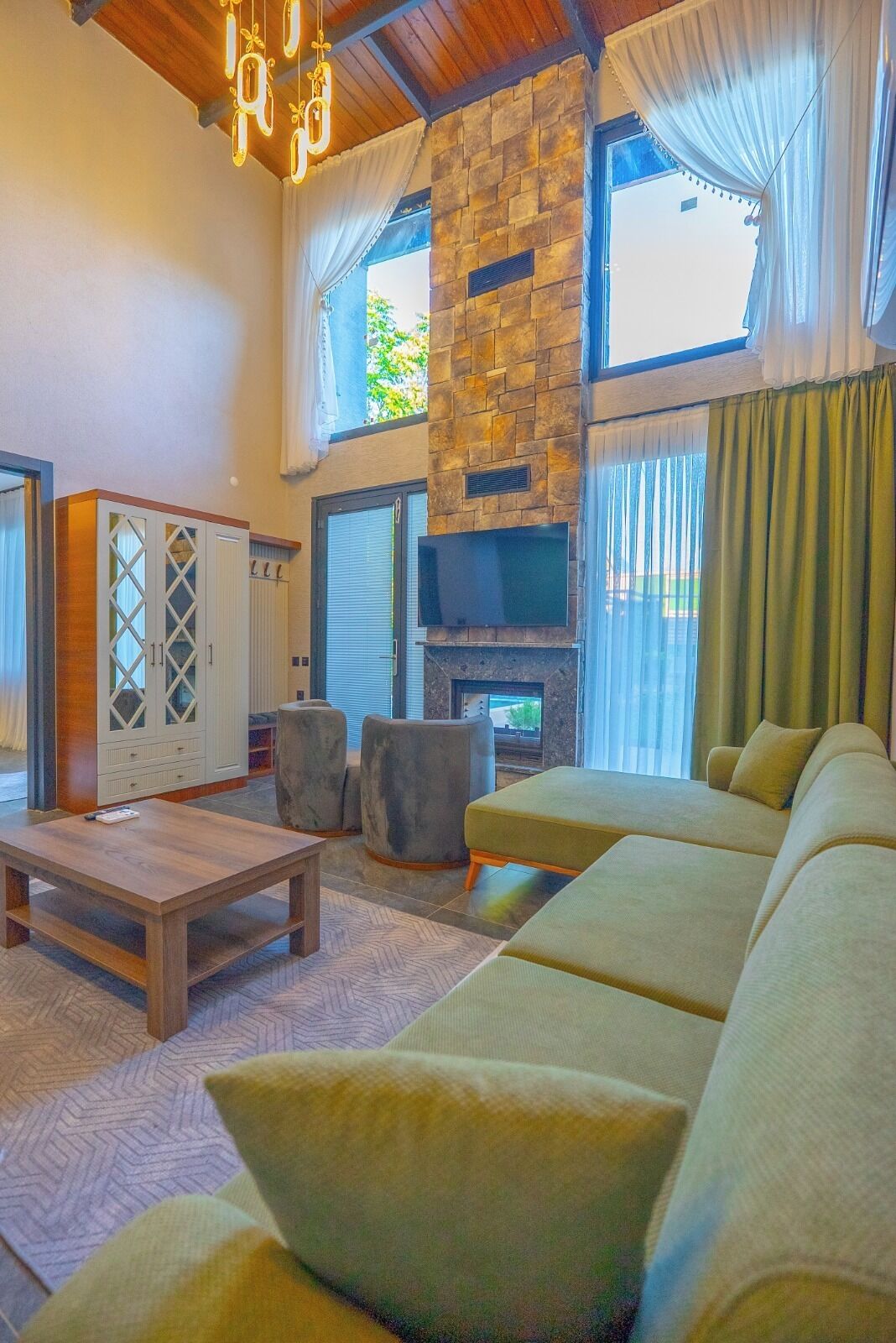 A living room with a stone fireplace, a sofa, a coffee table, and a television.