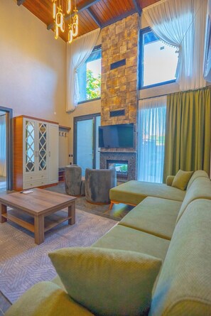 Una sala de estar con chimenea de piedra, un sofá, una mesa de centro y una televisión.