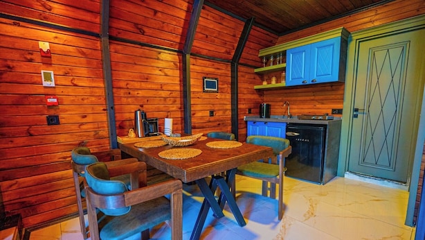 A wooden interior with a dining table, chairs, a kitchen area with blue cabinets, and a door with a geometric pattern. - Berra Resort (Sapanca)