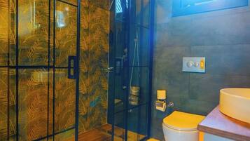 Un baño moderno con cabina de ducha de vidrio, inodoro y lavamanos.
