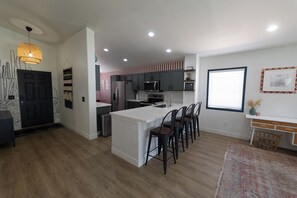 Una cocina moderna con una isla central, taburetes de bar y un comedor con un rug adornado.