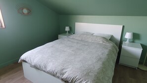A bedroom with a bed, nightstands, and a wall-mounted eye decoration. - Peaceful cottage overlooking the Rade de Brest, Crozon peninsula Brittany (Roscanvel)