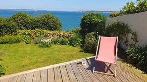A deck with a red chair, a stone wall, and a view of the sea. - Peaceful cottage overlooking the Rade de Brest, Crozon peninsula Brittany (Roscanvel)