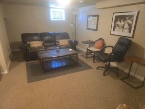 A living room with a leather sofa, a coffee table, a chair, and a small table with a lamp.