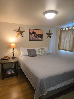 Een slaapkamer met een bed, nachtkastje, lamp en een sterren decoratie aan de muur.