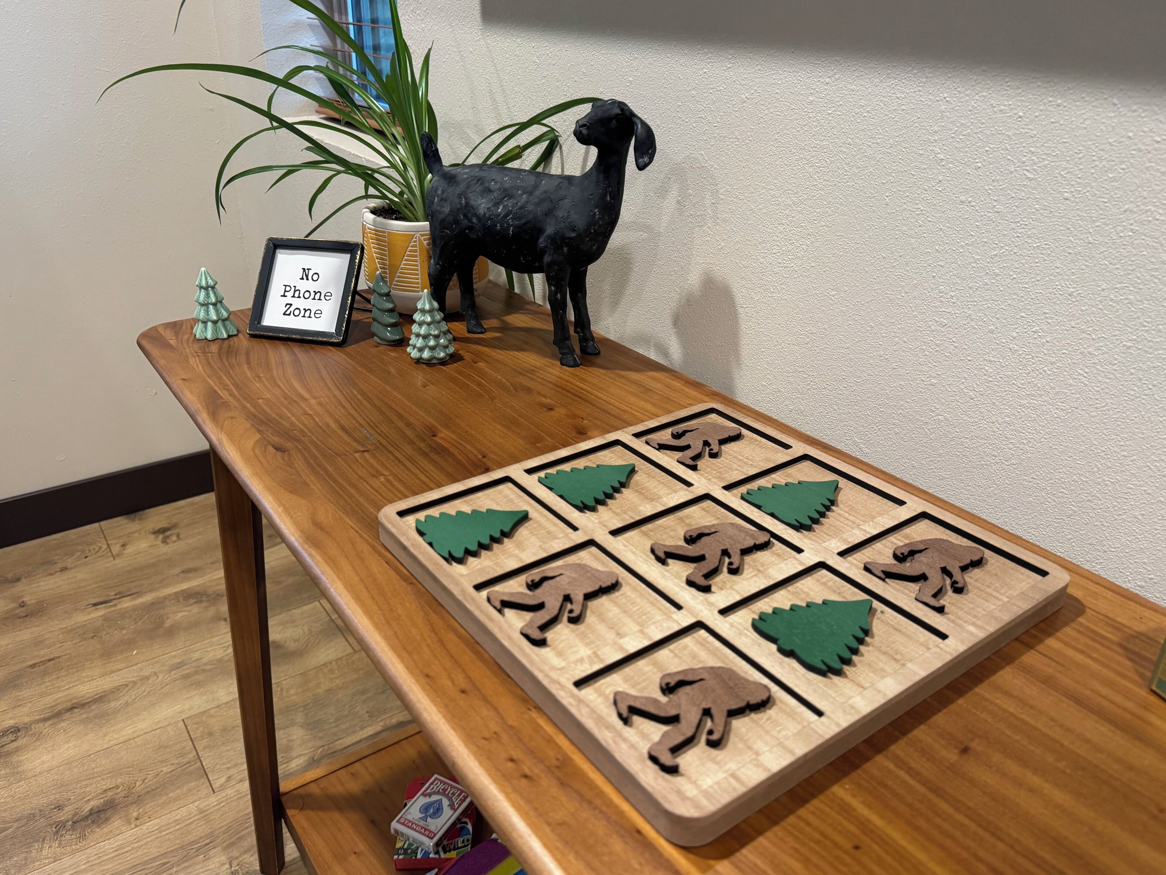 Une table en bois avec un jeu de puzzle, un panneau encadré et une plante en pot.