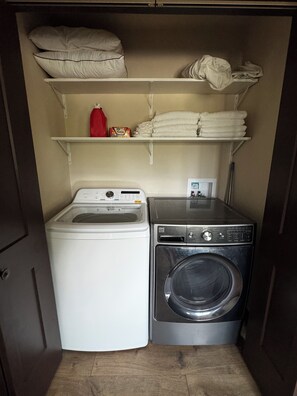 Une petite buanderie équipée d’un lave-linge à chargement frontal et d’un sèche-linge à chargement par le haut.