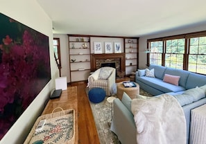 Ein Wohnzimmer mit Kamin, einer Couch, einem Sessel und einem Bücherregal.