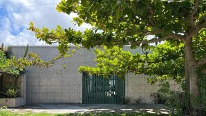 A building with a green gate, a grassy area, and a tree.