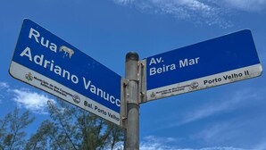 A directional signpost with two blue signs, one pointing to Rua Adriano Vanuc and the other to Av. Beira Mar.