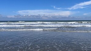 A beach with waves and a clear sky.