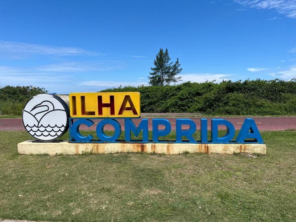 Un cartel con el texto 'ILHA COMPRIDA' y el logotipo de una ballena.