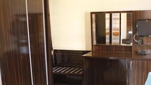 Una habitación con un armario de madera, un escritorio con computadora, una silla y un sofá.