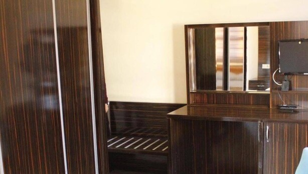 A room with a wooden wardrobe, a desk with a computer, a chair, and a sofa. - Özkonak Hotel (Ankara)