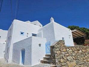Ein weißes Gebäude mit blauen Akzenten, Steinstufen und blauem, wolkenlosen Himmel.