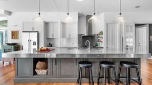 A modern kitchen with a central island, stainless steel appliances, and pendant lighting. - Heronwood - Luxury Country Retreat (Wattamolla)