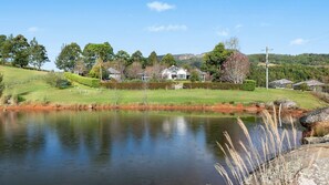 A serene lakeside property with a house, a pond, and surrounding greenery. - Heronwood - Luxury Country Retreat (Wattamolla)