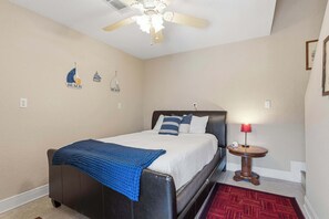 A bedroom with a bed, a nightstand, a red lamp, and wall decorations.