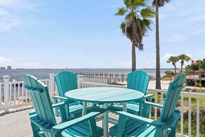 Une terrasse dotée de chaises turquoise et d’une table, offrant une vue sur une étendue d’eau avec une jetée au loin.
