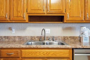 A kitchen with wooden cabinets, a granite countertop, a double sink, and a dishwasher.