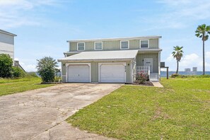 A two-story house with a garage, a front porch, and a view of the ocean.