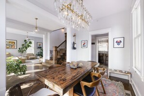A spacious dining area with a wooden table and chairs, a chandelier, and framed artwork on the walls. - Historic Mapleton Hill House (Boulder)