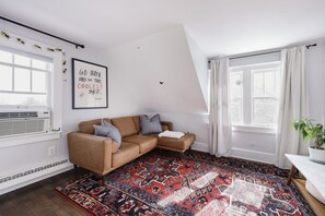 A modern living room with a brown leather sofa, patterned rug, and a framed quote on the wall. - Historic Mapleton Hill House (Boulder)