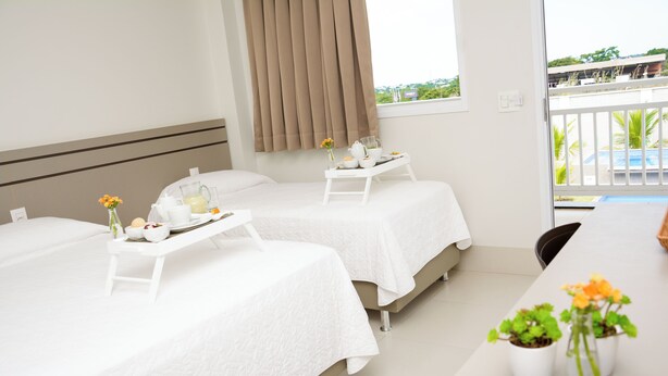 A hotel room with two beds, a balcony, and a breakfast tray on each bed. - Hotel Imperador (Gurupi)