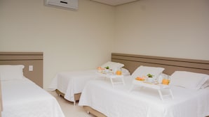 A hotel room with two single beds, a bedside table with a tray of breakfast items, and a wall-mounted air conditioning unit. - Hotel Imperador (Gurupi)