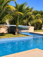 Una piscina con agua azul cristalina, rodeada de palmeras y un borde de azulejos.