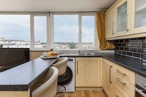 Eine kleine Küche mit eingebauter Waschmaschine, Spüle und Fenster mit Blick auf Gebäude.