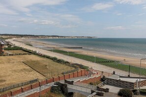Blick auf die Küste mit Strand, Promenade und einer Brücke.
