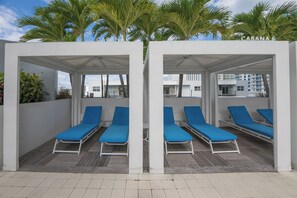 Ein überdachter Außenbereich mit blauen Lounge-Stühlen und einer weißen Wand.