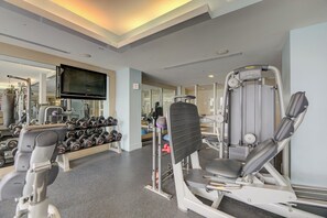 Una palestra con diverse attrezzature per esercizi, tra cui manubri, un televisore e uno specchio a parete.