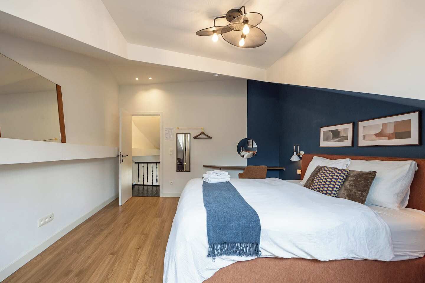 Een moderne slaapkamer met een groot bed, een hangende lamp en een deur naar een balkon.