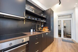 Una cocina moderna con armarios oscuros, estufa de acero inoxidable y horno empotrado.