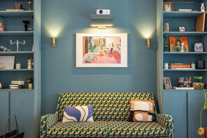 A room with a patterned sofa, a framed artwork above it, and shelves with various items. - Stylish 4BR Home in Antwerp Centre | Sleeps 9 Guests (Antwerp)