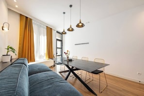 A modern living room with a sofa, dining table, chairs, and pendant lighting. - Stylish 4BR Home in Antwerp Centre | Sleeps 9 Guests (Antwerp)