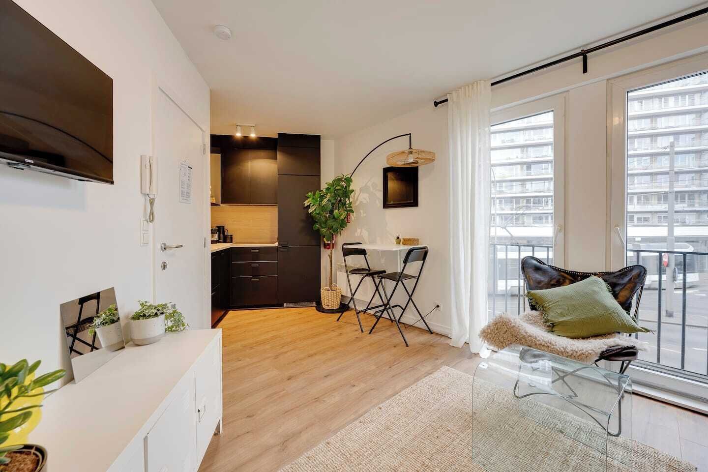 A modern apartment with a kitchen, dining area, and a balcony with a view.