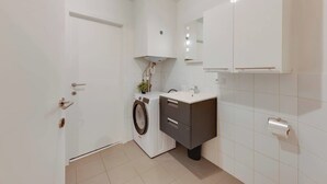 Un bagno compatto con lavatrice, lavandino e WC.